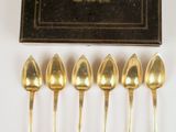 six cuillères en or dans une boîte, avec une boîte noire en arrière-plan