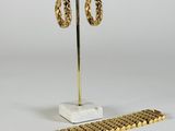 a pair of gold hoop earrings on a stand next to a ruler