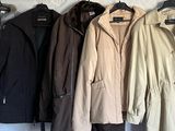 trois manteaux accrochés à un mur, avec un porte-manteau devant eux