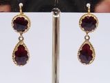 pair of garnet stone earrings on a gold plated stand