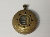 a close up of a small gold pocket watch on a white surface