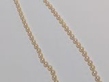 a close up of a pearl necklace on a white surface