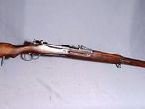 Un vieux fusil est posé sur une surface blanche, à côté d'un chapeau vert.