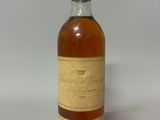 une vieille bouteille de whisky posée sur une surface blanche