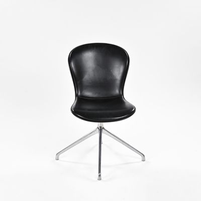 La chaise est noire, avec un piètement chromé et une assise en cuir noir.
