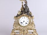 a gold clock with a statue on top of it