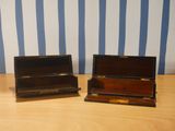 two wooden boxes sitting on a table with blue and white striped wallpaper