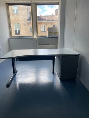 un bureau dans un coin d'une pièce, avec une fenêtre en arrière-plan