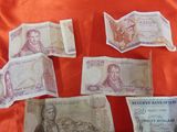 several bills of different currency are laid out on a red cloth