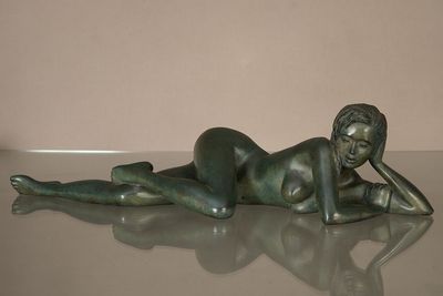 statue d'une femme allongée sur le ventre sur une table en verre