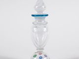 a glass vase with a blue top on a white surface