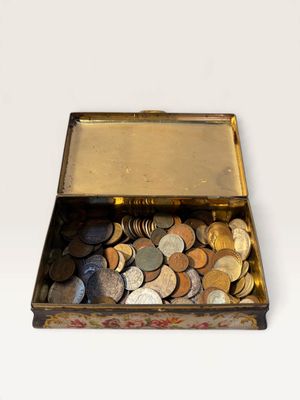 a small metal box filled with coins on a white surface