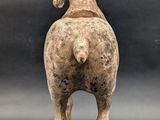 statue of a horse standing on a wooden base against a black background