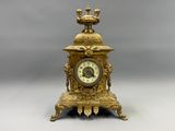 a gold clock with a bird on top of it