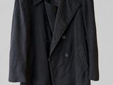 a black jacket hanging on a hanger on a white wall