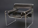 une image représentant une chaise en cuir noir et chrome sur fond gris