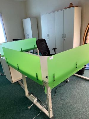 a green desk with a black chair in a room