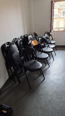 des rangées de chaises noires dans une pièce avec une fenêtre à l'arrière-plan