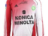 Le t-shirt est rouge et blanc, avec un logo noir dessus.