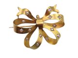 an image of a gold bow brooch with pearls on it