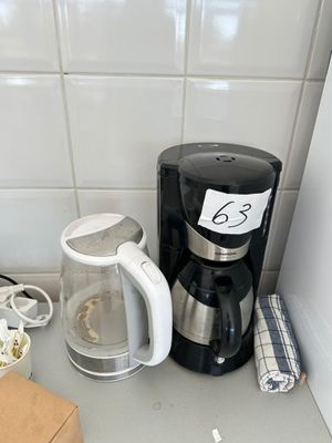 a coffee maker on the counter next to a cup of coffee