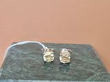 une paire de boucles d'oreilles en argent posée sur une table en marbre avec un fond rose