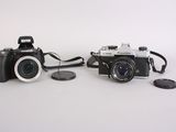 two cameras sitting next to each other on a white surface