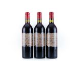 trois bouteilles de vin rouge posées l'une à côté de l'autre sur une surface blanche