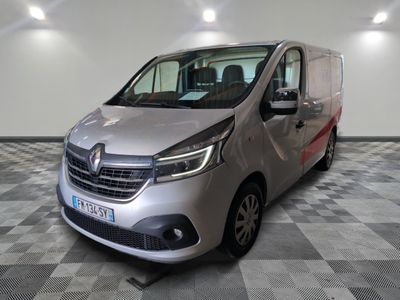 La camionnette argentée est garée sur un sol à damier dans un garage.