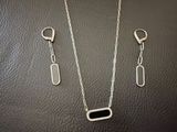 un ensemble composé d'un collier et de boucles d'oreilles en argent, posé sur un fond en cuir noir