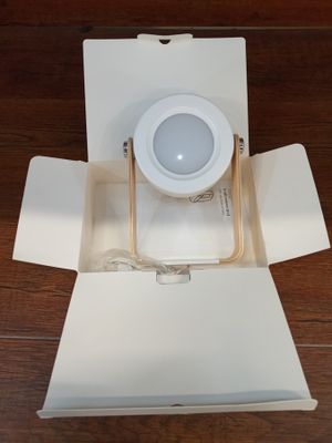 une boîte blanche avec une lumière à l'intérieur, posée sur un plancher en bois