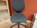 une chaise de bureau grise placée devant une bibliothèque