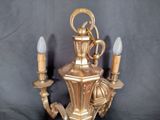 a gold wall light that is on a black background