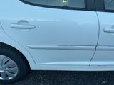 une voiture blanche garée sur un parking, dont la portière est ouverte