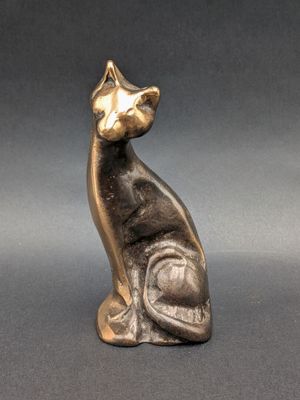 statue of a cat sitting on its hind legs on a gray surface