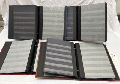 Plusieurs classeurs sont alignés sur un lit recouvert d'un drap blanc