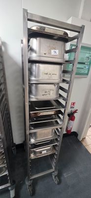 several trays of food sit on a metal rack in a kitchen