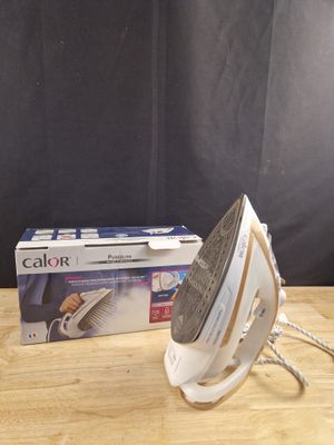 une boîte et un fer à repasser posés sur une table, sur fond noir