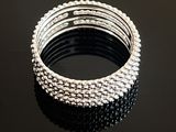 a close up of a stack of silver bracelets on a black surface