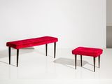 un banc rouge et un pouf rouge dans une pièce blanche