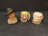 trois figurines en céramique représentant des hommes portant un chapeau et une barbe, posées sur un fond noir