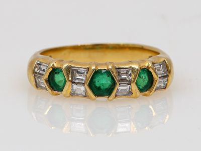 Gros plan sur une bague en or ornée d'émeraudes et de diamants