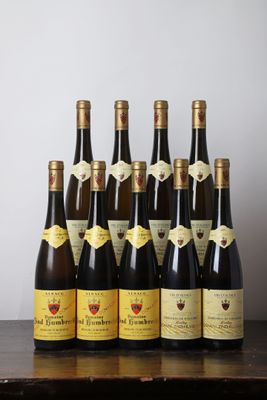 Des bouteilles de vin sont alignées sur une table devant un mur blanc