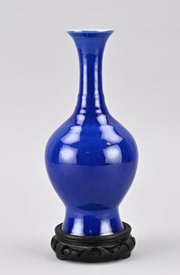 un vase bleu avec un socle noir sur fond blanc