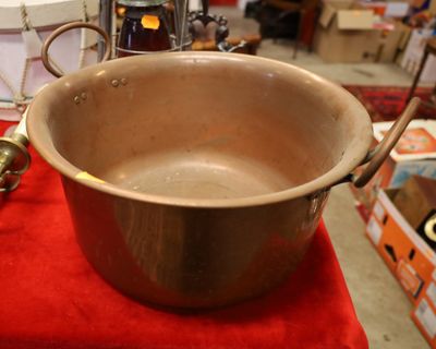 une grande casserole en métal posée sur une table rouge