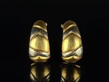 une paire de boucles d'oreilles en or et en argent posées sur un fond noir