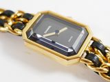 a gold watch with a black face on a chain bracelet