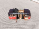 a small red bus with luggage on top of it