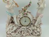 deux figurines posées sur une horloge, elle-même posée sur une table