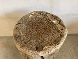 a stone stool sitting on the floor in front of a wall